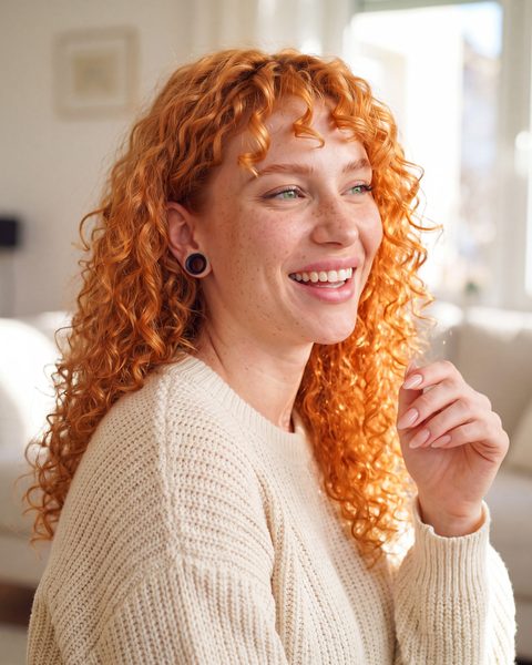 Freya laughing at home in a chunky cream knit sweater.